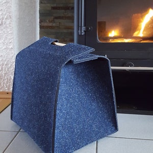 Könnte beinhalten: Ein blauer Filz-Holzträger mit einem Holzgriff. Der Träger steht vor einem Kamin mit einem Feuer, das darin brennt.