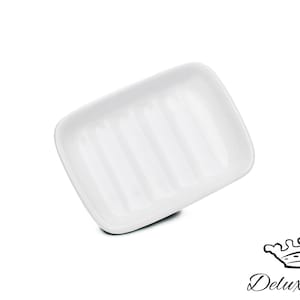 Può includere: Portasapone in ceramica bianca con creste rialzate sul fondo. Il portasapone è progettato per contenere una saponetta e permettere all'acqua di scolare.