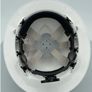 May include: White hard hat with a black suspension system and a black chin strap. The suspension system has a gray webbing and a gray pad.