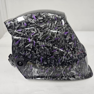 May include: A black welding helmet with a purple and black carbon fiber pattern.