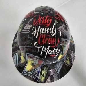 May include: A black hard hat with a design of dollar bills and the words "Dirty Hands, Clean Money" in red and white lettering.