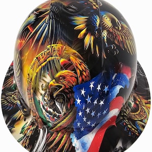 May include: A black hard hat with a vibrant design featuring eagles, the American flag, and Mexican imagery. The artwork incorporates red, yellow, blue, and white colors, creating a patriotic and artistic appearance. The hard hat is designed for construction or industrial use.