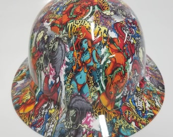 May include: A white hard hat with a colorful graphic print featuring a pirate theme, skulls, and flames. The print includes the text "Hot Mess Gang".
