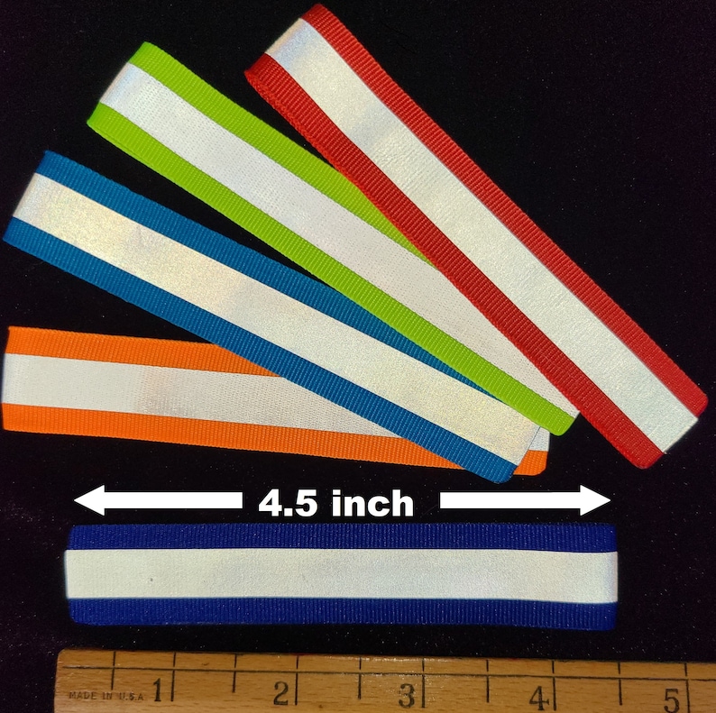 K&ouml;nnte beinhalten: F&uuml;nf reflektierende Bandstreifen in verschiedenen Farben, darunter Orange, Blau, Gr&uuml;n und Rot, mit einem wei&szlig;en reflektierenden Streifen in der Mitte. Die Bandstreifen sind 4,5 Zoll lang.
