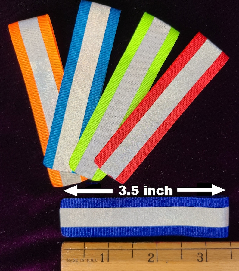 K&ouml;nnte beinhalten: F&uuml;nf reflektierende Stoffstreifen in verschiedenen Farben: Orange, Blau, Gr&uuml;n, Rot und Blau. Die Streifen sind 8,9 cm lang und haben einen wei&szlig;en reflektierenden Streifen in der Mitte.