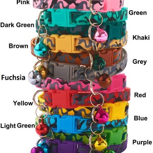 May include: A stack of ten colourful cat collars with a camouflage pattern and a bell on each collar. The collars are in the following colours: pink, dark green, brown, fuchsia, green, khaki, grey, yellow, red, light green, blue, and purple.