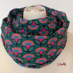 May include: Teal blue infinity scarf with a repeating pattern of pink, orange and purple flowers. The flowers have a retro design with a circle in the centre.