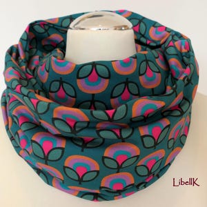 May include: Teal infinity scarf with a repeating pattern of pink, orange, and turquoise flowers. The scarf is made of a soft, comfortable fabric and is perfect for keeping warm in the winter.