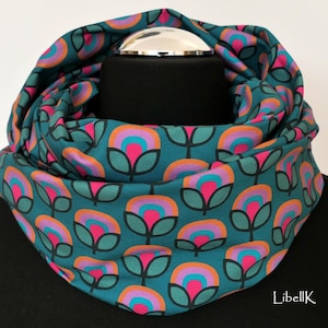 May include: A teal blue infinity scarf with a repeating pattern of pink, orange, and turquoise flowers.