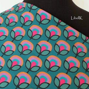 May include: Teal fabric with a repeating pattern of stylised flowers in shades of pink, orange, and purple. The flowers have a retro, 70s aesthetic.