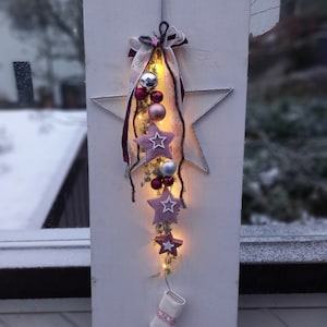 Könnte beinhalten: Eine rosafarbene und weiße sternförmige Weihnachtsdekoration mit Lichtern, rosafarbenen Filzsternen und Anhängern.