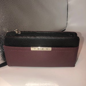 May include: A burgundy leather wallet with a black leather flap and a silver metal plate that reads "...EST...RELIC...1992..."