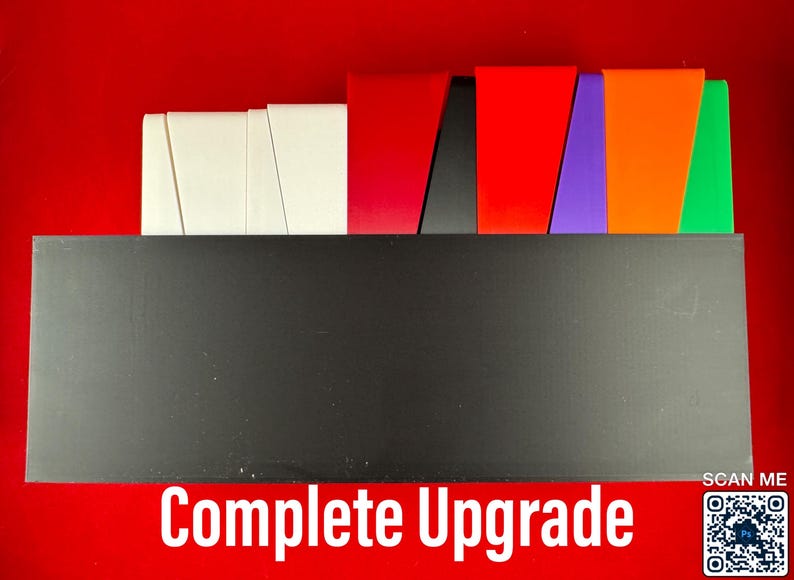 May include: A black box with the text "Complete Upgrade" on the front. The box is sitting on a red surface. There are several colored pieces of paper stacked on top of the box.