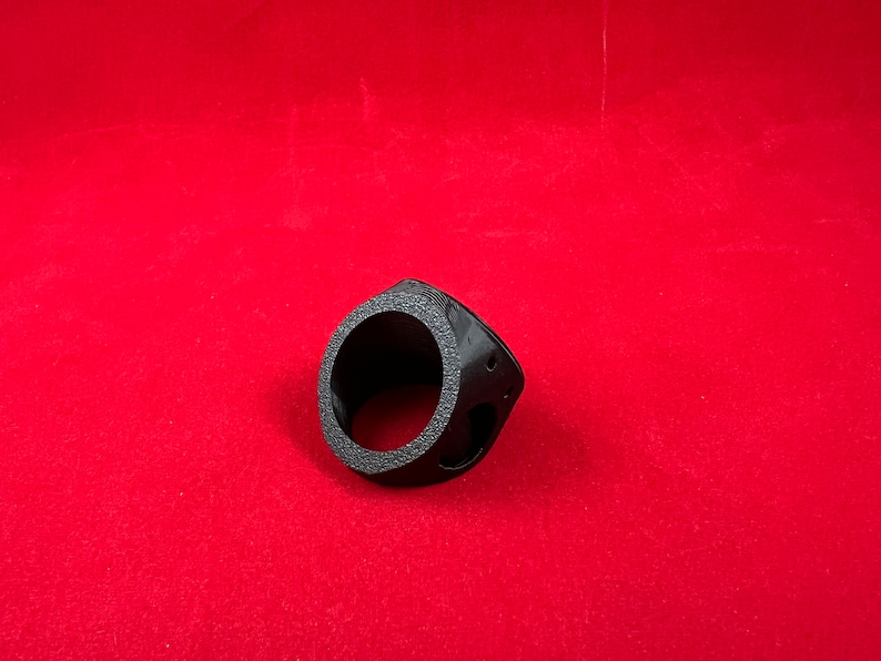May include: A black plastic ring with a circular opening and a textured surface. The ring is designed to fit around a pipe or other cylindrical object.
