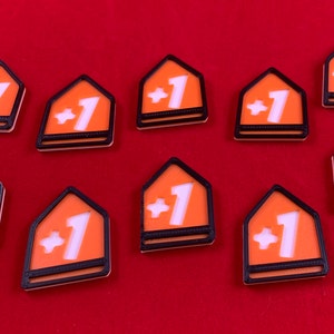Op de afbeelding: Tien oranje en zwarte plastic tokens met een wit plusteken en het nummer &eacute;&eacute;n op elk.