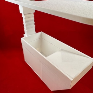May include: White plastic shelf unit with a small rectangular tray and a larger rectangular tray below. The shelf unit is designed to be mounted on a wall.