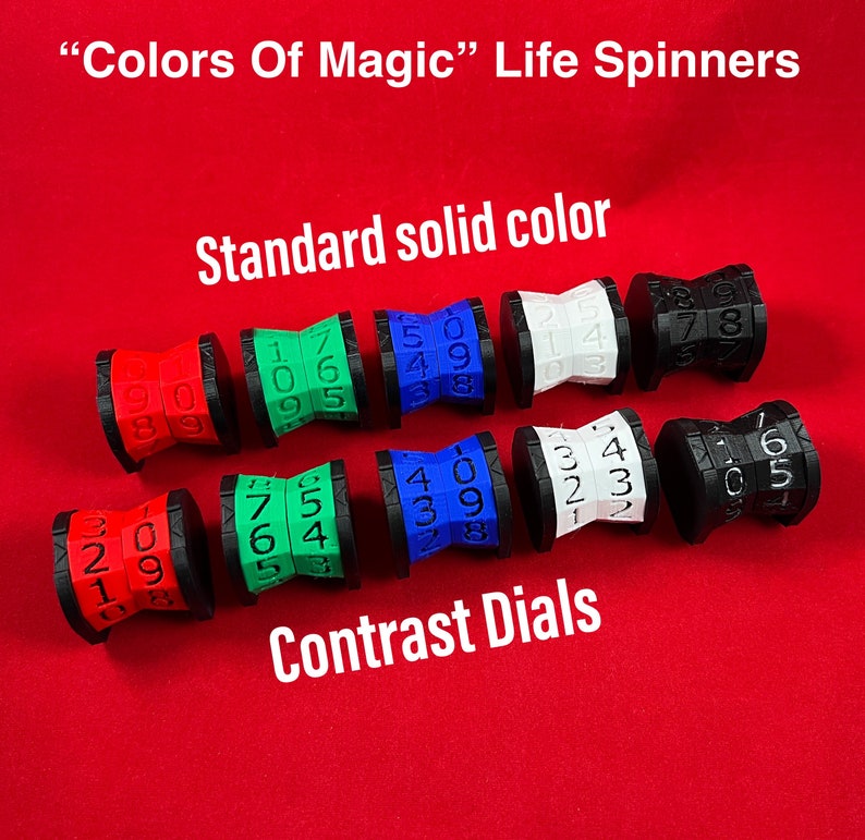 May include: Eight life counters, or spinners, in various colors, including red, blue, green, white, and black. Each counter has a number dial with numbers 0-9. The counters are labeled "Standard solid color" and "Contrast Dials".