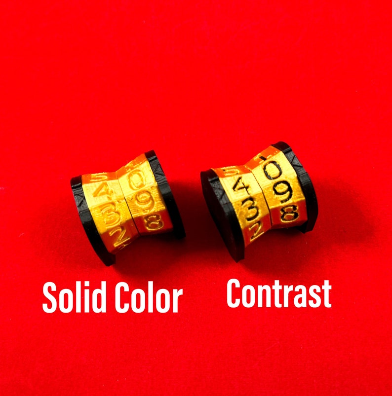 May include: Two gold-colored number wheels with black bases. The wheel on the left has the numbers 4627 and 098. The wheel on the right has the numbers 4321 and 098. The text "Solid Color" is below the left wheel and "Contrast" is below the right wheel.