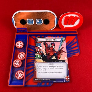 Op de afbeelding: Een rood en blauw spelbord met een Spider-Man-personagekaart. De kaart heeft een afbeelding van Spider-Man die aan een web slingert. De tekst op de kaart luidt "Spider-Sense - Onderbreken: Wanneer de schurk een aanval tegen je start, trek 1 kaart. "Je vriendelijke buurtspiderman."  Handgrootte 5/Treffers 10"