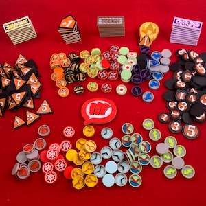 Op de afbeelding: Een verzameling spelstukken voor een bordspel. De stukken zijn gemaakt van plastic en zijn verkrijgbaar in verschillende kleuren, waaronder rood, blauw, groen, geel en zwart. Er zijn ook wat dobbelstenen en kaarten op de afbeelding.