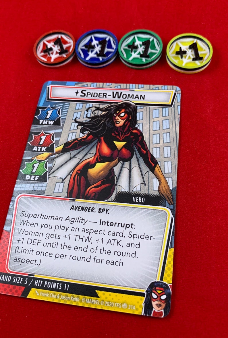 Op de afbeelding: Een Spider-Woman-verzamelkaart uit het Marvel Champions-spel. De kaart toont een illustratie van Spider-Woman in haar rood-gele kostuum met een wit spinnen-symbool op haar borst. De tekst op de kaart luidt "Superhuman Agility - Interrupt: When you play an aspect card, Spider-Woman gets +1 THW, +1 ATK, and +1 DEF until the end of the round. (Limit once per round for each aspect.)" De kaart heeft ook een handgrootte van 5 en 11 trefferpunten.
