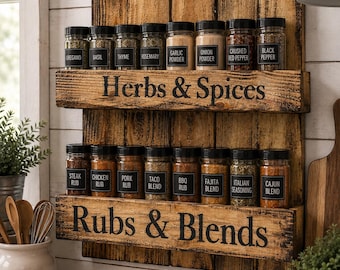 Puede incluir: Un especiero de madera de dos niveles con un acabado oscuro y desgastado. El estante superior tiene la etiqueta "Herbs & Spices" y contiene ocho frascos de vidrio con tapas y etiquetas negras. El estante inferior tiene la etiqueta "Rubs & Blends" y contiene ocho frascos a juego.