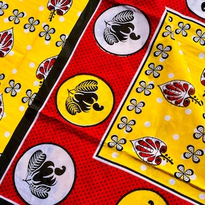 Puede incluir: Primer plano de tela colorida con un patrón repetitivo. La tela presenta un fondo amarillo con lunares blancos y diseños de hojas rojas y blancas. También hay diseños florales y de hojas en blanco y negro. La palabra "MSHUKURU" es visible.