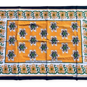 Puede incluir: Textil rectangular con un patrón floral repetido. El centro es amarillo con flores blancas y azules. El borde es blanco con diseños florales verdes y amarillos, enmarcado por un borde azul marino. El texto es visible en el centro.