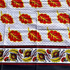 May include: White fabric with a repeating pattern of red and yellow leaves on a dotted background. The bottom features a decorative border with floral and leaf designs in yellow, red, and black.