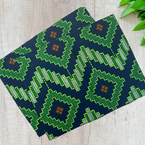May include: Two fabric placemats with a geometric pattern in shades of green, blue, and brown. The pattern features a repeating design of squares and rectangles.