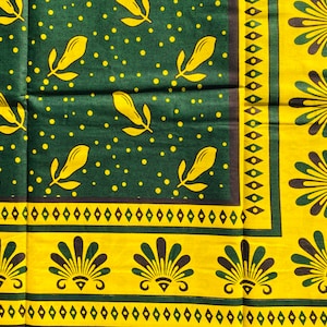 May include: A green and yellow fabric with a repeating pattern of leaves and dots. The fabric has a border with a repeating pattern of stylized shells.