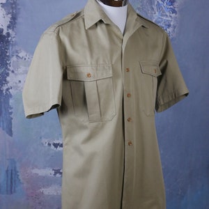 May include: A khaki short-sleeved button-down shirt with two flap pockets and a pointed collar.