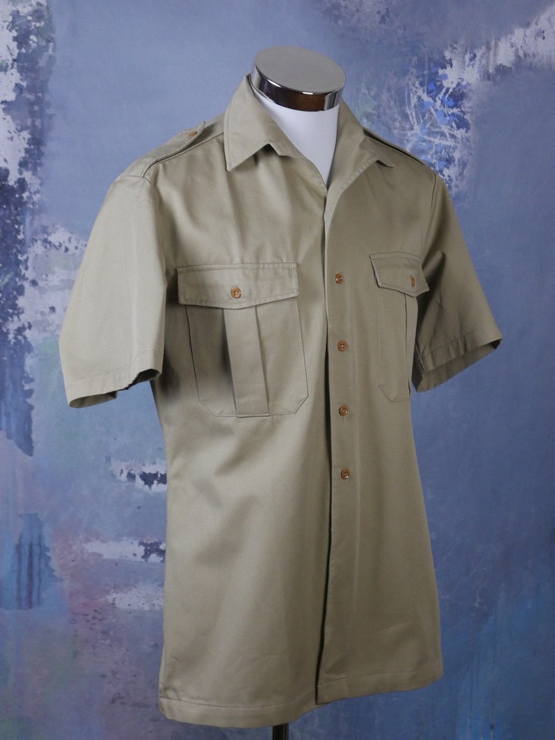May include: A khaki short-sleeved button-down shirt with two flap pockets and a pointed collar.