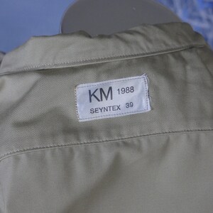 May include: A beige shirt with a white label that reads "KM 1988 SEYNTEX 39".