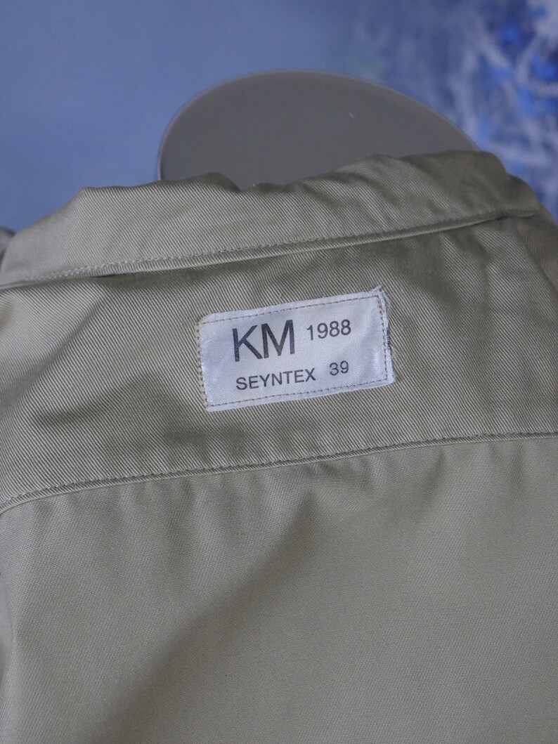 May include: A beige shirt with a white label that reads "KM 1988 SEYNTEX 39".