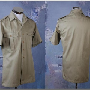 May include: A khaki short-sleeved button-down shirt with two large flap pockets on the front. The shirt has a pointed collar and a button closure.