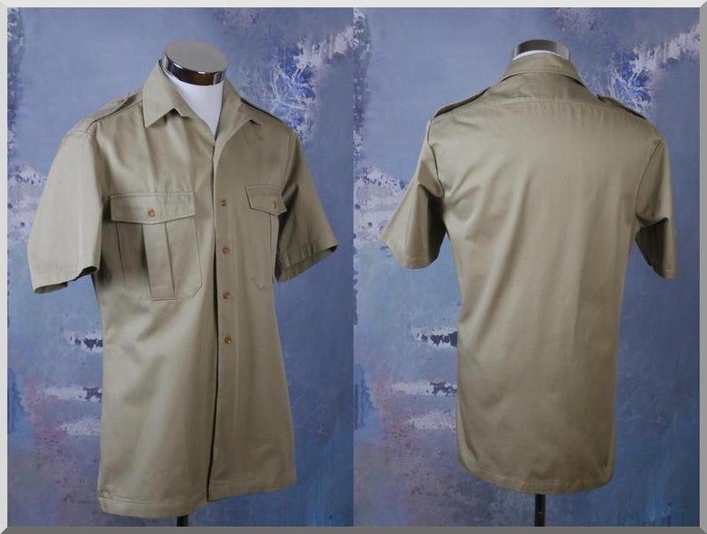 May include: A khaki short-sleeved button-down shirt with two large flap pockets on the front. The shirt has a pointed collar and a button closure.