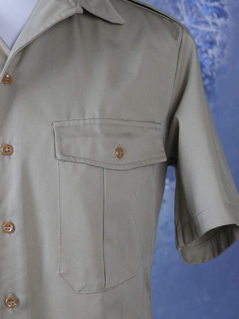 May include: A light brown short-sleeved shirt with a button-up front and a single chest pocket.