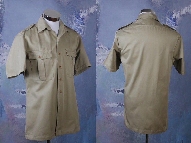May include: A khaki short-sleeved button-down shirt with two flap pockets on the front and a button-down collar.