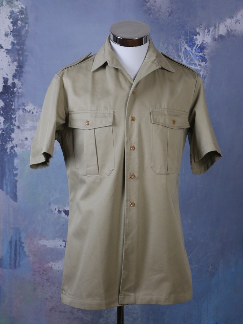 May include: A beige short-sleeved button-down shirt with two flap pockets and a pointed collar.