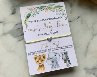 May include: A yellow and white card with green foliage and animal illustrations. The card says "Thank you for celebrating Louise's Baby Shower 29th August 2021". A yellow string bracelet with a silver heart charm is attached to the card. The card says "Make a Wish" and includes instructions for making a wish.