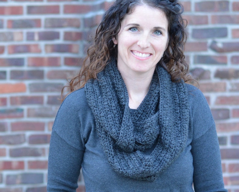 Smiling woman wearing a charcoal sweater and handmade infinity scarf