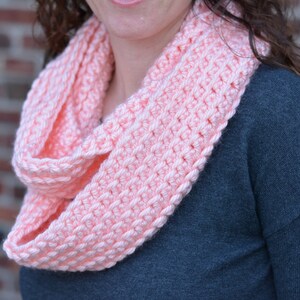 May include: A soft pink crocheted infinity scarf. The scarf is made with a simple stitch pattern and is perfect for keeping warm in the winter.