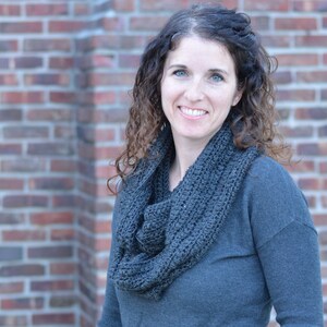 Smiling woman wearing a charcoal sweater and handmade infinity scarf
