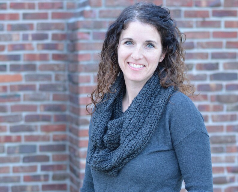 Smiling woman wearing a charcoal sweater and handmade infinity scarf
