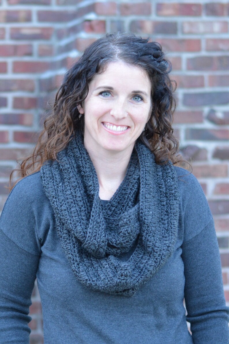 Smiling woman wearing a charcoal sweater and handmade infinity scarf