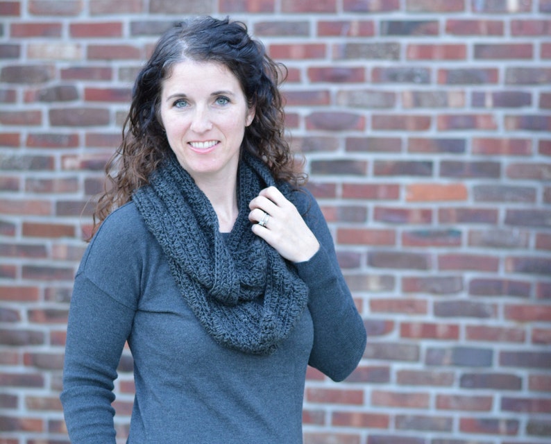Smiling woman wearing a charcoal sweater and handmade infinity scarf