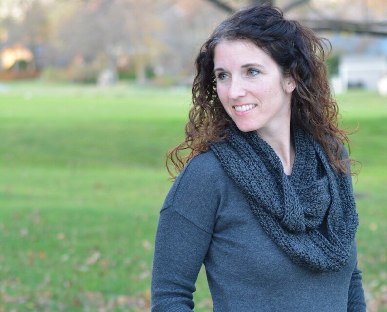 Smiling woman wearing a charcoal sweater and handmade infinity scarf