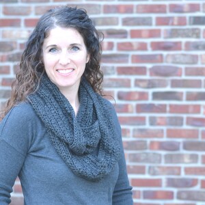 Smiling woman wearing a charcoal sweater and handmade infinity scarf