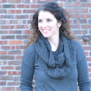 Smiling woman wearing a charcoal sweater and handmade infinity scarf